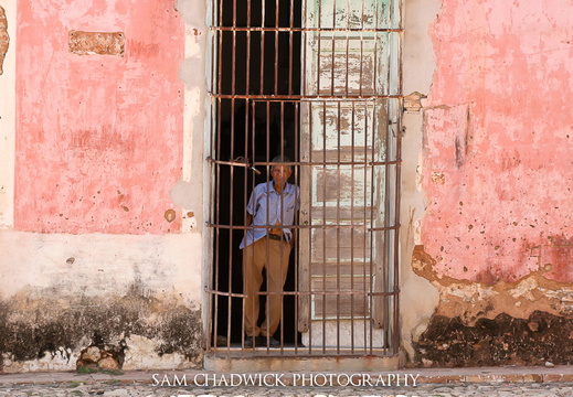 Man standing in gated doorway of an old building in Trinidad Cub