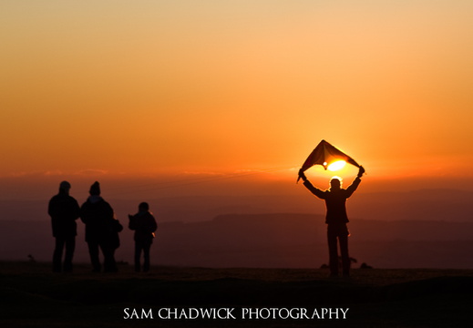 Man launching a kite at sunset