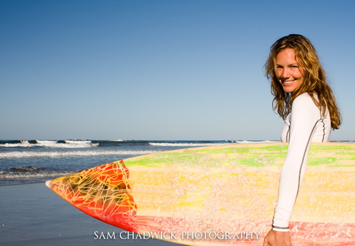 Girl standing with surfboard